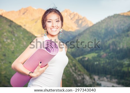 Happy asian woman with yoga mat going to play in sports or fitness exercises outdoor at mountain. Healthy lifestyles concept of body and soul