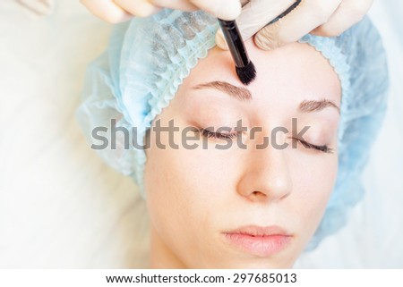 Professional woman at spa beauty salon doing correction using medical brush. You can see her smooth eyebrow after hair removal