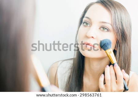makeup artist woman doing make-up using cosmetic brush applying eye shadow on face for yourself at beauty salon with white background