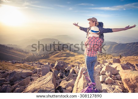 Hike and adventure at top of mountain of achieve and successful couple, young man and woman, with aerial view of mountain range. They dressed in pants, shirt, fashion heat and backpack