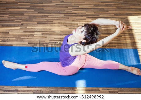 Asian woman doing splits for yoga exercise indoor at home. She looking up. Top view. Concept of sports at home