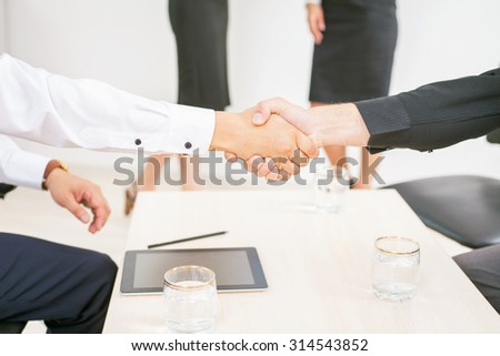 concept of business success - two men shaking hands and there are a two business woman at white background for any text and copy space