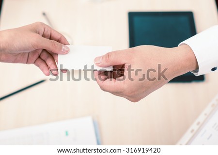 successful deal, businessman gives businesswoman a business card or visit card with a white background on a blank for copy space and any contacts or phone number. Monochromatic color
