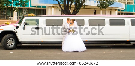 Portrait of beautiful happy wedding couple, Just Married opposite limousine