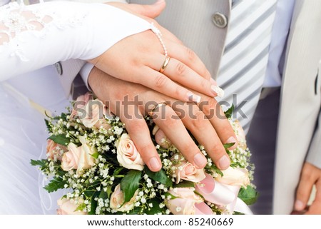 The hands of just married couple on the flowers background