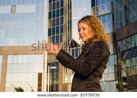 Woman looking at credit card, or doing shopping and paying opposite office building