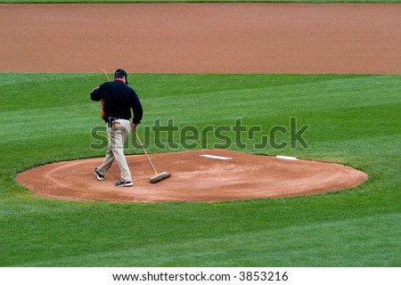 Grounskeeper that is grooming a pitchers mound