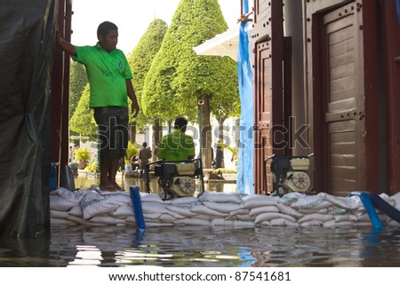 BANGKOK, THAILAND - OCTOBER 27 : An unidentified man helps bring sandbags to protect Wat Phra Kaew from rising flood waters on October 27, 2011 in Bangkok, Thailand.