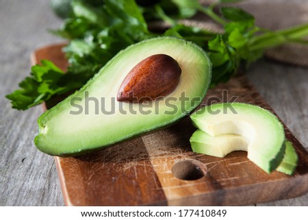 Fresh avocado on cutting board on old wooden background