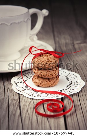 Cup of tea or coffee and almond cookies served on old wooden table