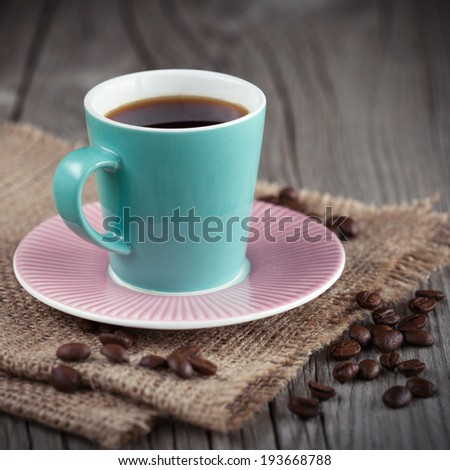 Cup of espresso with coffee beans on dark wooden background, selective focus