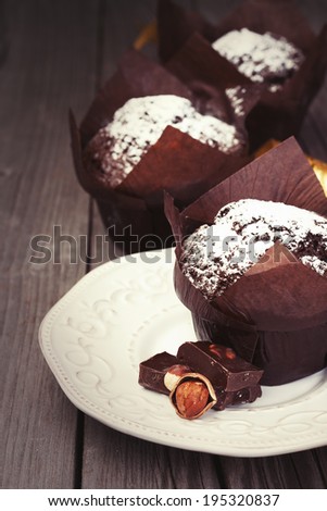 Homemade chocolate muffins with powder sugar on dark wooden background