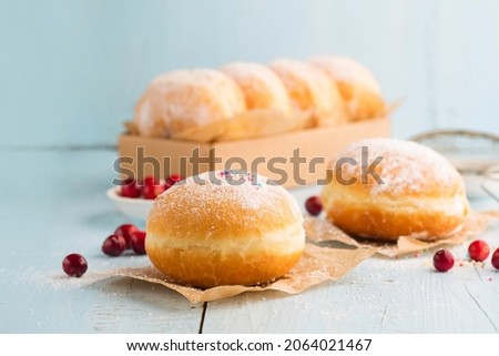 Hanukkah sweet food doughnuts sufganiyot with powdered sugar and fruit jam on blue wooden background. Jewish holiday Hanukkah concept. 