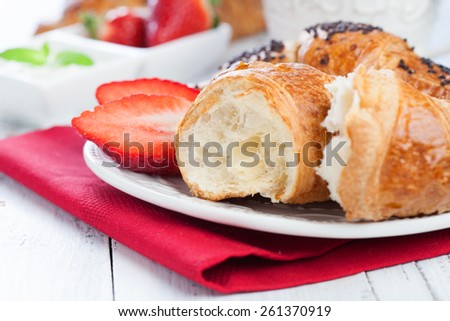 Morning breakfast with fresh croissants yogurt and strawberry on white wooden table