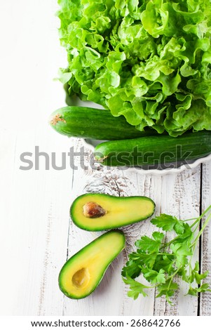 Fresh green vegetables on white wooden background, top view
