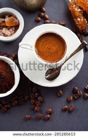 Cup of coffee espresso, brown sugar and roasted beans on dark background, top view