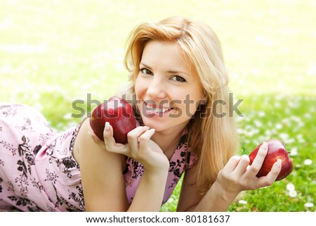 Beautiful young blonde woman relaxing on a meadow with apples