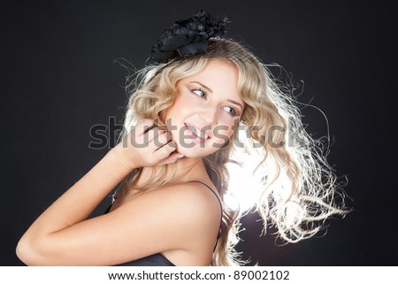 Close-up portrait of fresh and beautiful young fashion model  with big black flower in hair over black
