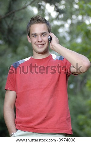 Picture of young leisure time dressed man with cell phone in park talking while walk