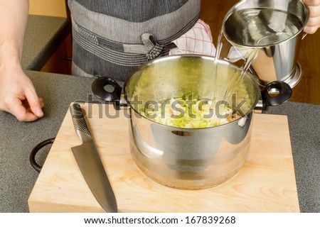 Water poured into cooking pan by male hands on wooden cutting board
