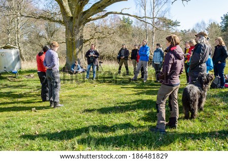 KALMAR, SWEDEN - APRIL 05, 2014: Two female nature guides showing map on guide tour. Group standing around to listen.