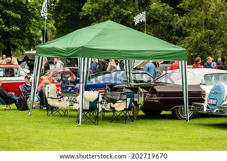 RONNEBY, SWEDEN - JUNE 28, 2014: Nostalgia Festival with classic cars and motorcycles as main attractions. Green roofed party tent over trunk of car and seats.