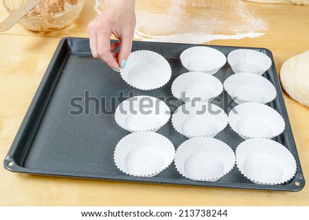 White disposable paper baking cups placed on metal baking sheet.