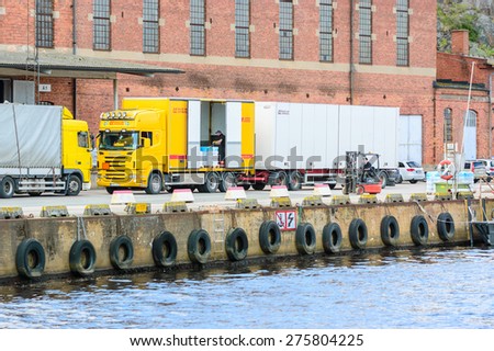 KARLSHAMN, SWEDEN - MAY 06, 2015: Two unknown male worker unload a truck at the docks outside an old factory building. One is driving a forklift, the other is inside truck.
