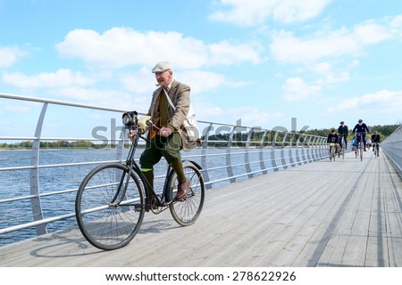 SOLVESBORG, SWEDEN - MAY 16, 2015: International Veteran Cycle Association (IVCA) 35th rally. Costume ride through public streets in town. Senior man on bridge.