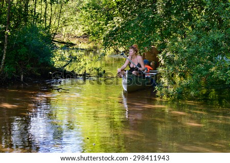 STORA TUNA, SWEDEN - JULY 02, 2015: Family appearing on calm river in a canoe. Female sits first and is ready to leave the canoe and walk in the shallow water. Nature tourism is booming in Sweden.