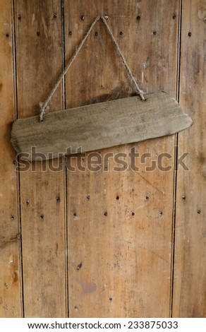 Blank sign hanging from a nail on an old rustic wooden oak weathered front door.