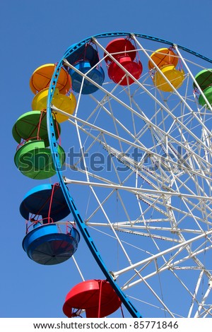 A colourful ferris wheel against a deep blue sky. Diagonal view
