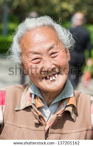 SHANGHAI, CHINA - APR 7, 2013: old chinese woman friendly toothless toothy smiling outddors portrait  at the city of Shanghai in China on april 7th, 2013