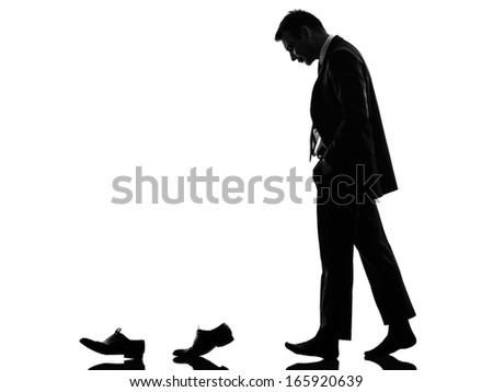 one caucasian business man walking behind his shoes   in silhouette  on white background