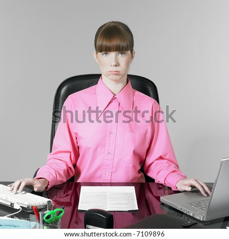 studio shot of a expressive and funny red hair young woman at the office desk having a hard time