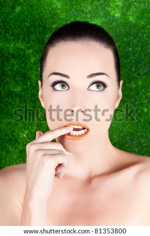 Closeup portrait of a beautiful nervous woman biting her finger while looking up isolated on green