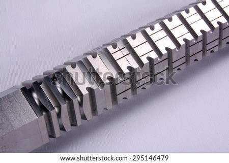 A well engineered broach used in automobile parts, on white studio cloth background.