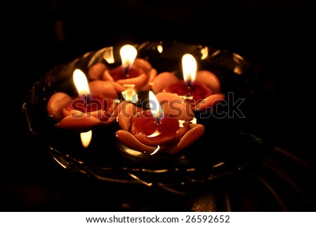 A view of floating rose candles in a bowl of water, lit on the occasion of Diwali festival in India. Focus on candle.