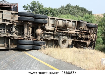 A view of the rear wheels of a skidded overturned truck on an highway in an accident.