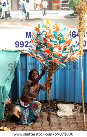 PUNE, MAHARASHTRA/INDIA August 15: A poor street-side peddler woman prepares flags and windmills of Indian flags to sell on 64th Indian Independence Day on August 15, 2010 in Pune, Maharashtra, India.
