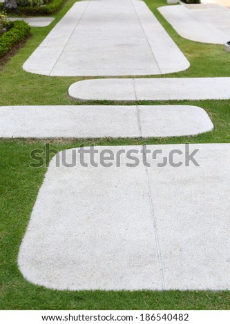 The cement walk path in the park with green grass background
