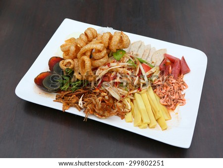 Thai spicy papaya salad serve with preserved egg, shoot, pork rind and crab