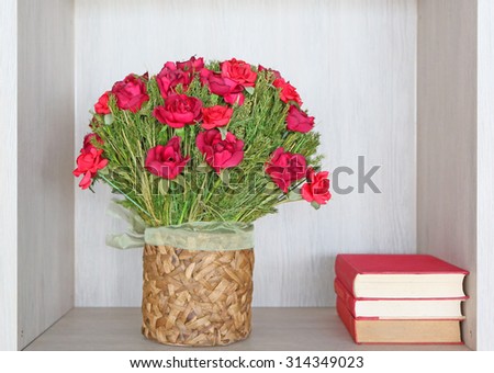 Bouquet of artificial red roses in recycle vase and books