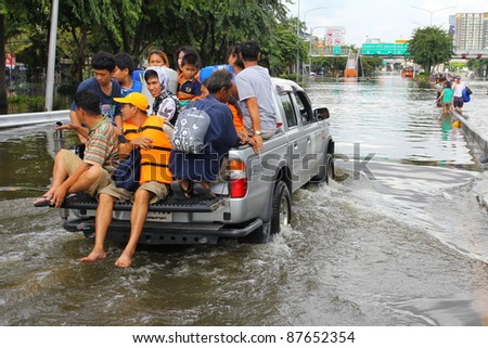BANGKOK, THAILAND - OCTOBER 29 : Unidentified people sit and stand in car to escape rising flood waters at Pinklao Bridge in Bangkok, Thailand on Oct. 29, 2011.