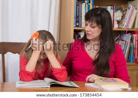 A mother consoles her young daughter when she gets discouraged trying to do her homework.