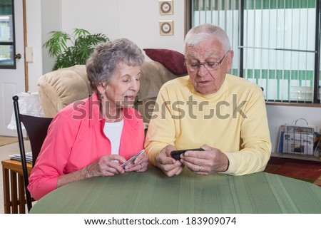 An elderly couple in their mid-eighties work together to figure out their new phone.