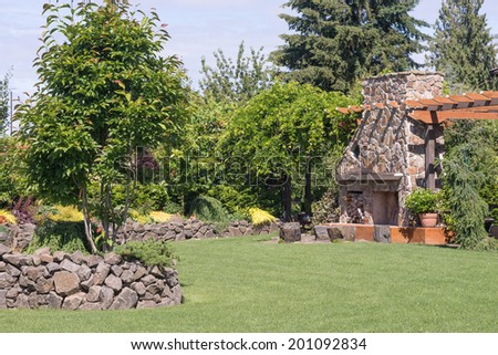 A huge fireplace with sitting stones in front of it is the centerpiece for this beautifully landscaped sunken garden surrounded by a dry built stone wall.