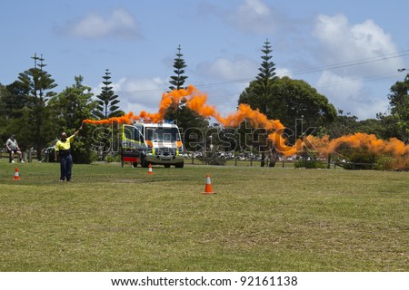 MOLLYMOOK, NSW, AUSTRALIA - CIRCA DEC 2011:Man holds smoke flare to signal ambulance helicopter for landing at Mollymook Beach on December 30, 2011.