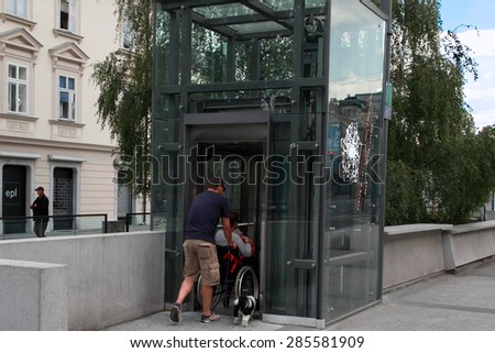 LJUBLJANA, SLOVENIA -  JUNE 28, 2014: Husband and wife in a wheelchair with a dog come in passenger lift. LJUBLJANA, JUNE 28, 2014