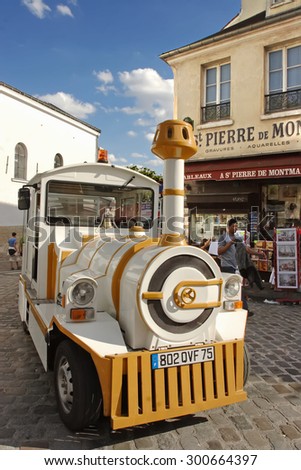 PARIS, FRANCE, August 19, 2014. Small train for tourists stops in front of souvenir stores. Montmartre is one of the most touristic district in Paris. PARIS, FRANCE, August 19, 2014.